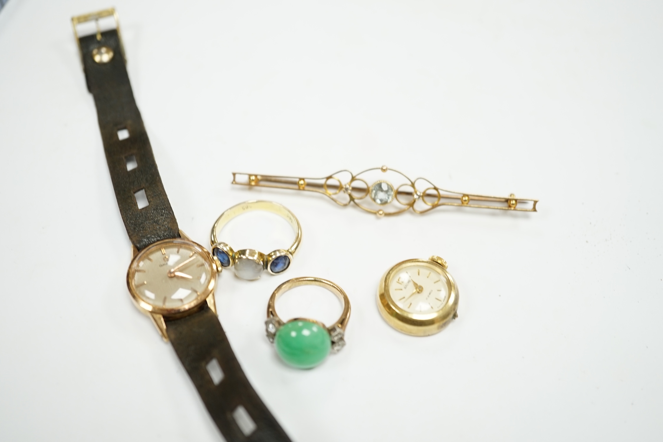 An Edwardian 15ct, aquamarine and diamond set three stone bar brooch, 74mm, a lady's yellow metal Omega manual wind wrist watch, a lady's rolled gold wrist watch a 14k and three stone sapphire ring the central stone a wh